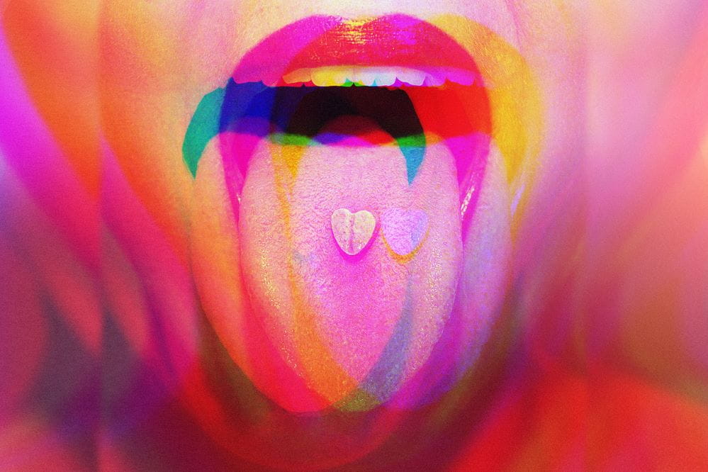 Young woman with colorful psychoactive drug pills on her tongue having psychedelic trip with hallucinations.