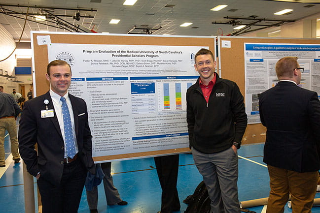 Research Day presenters standing by poster