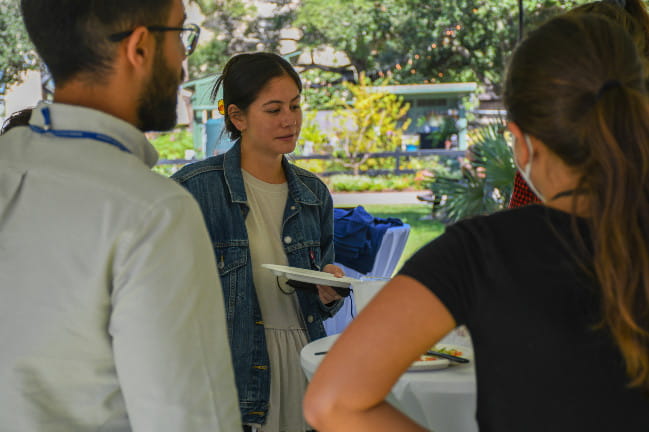 A group of students speak together somewhere outdoors.